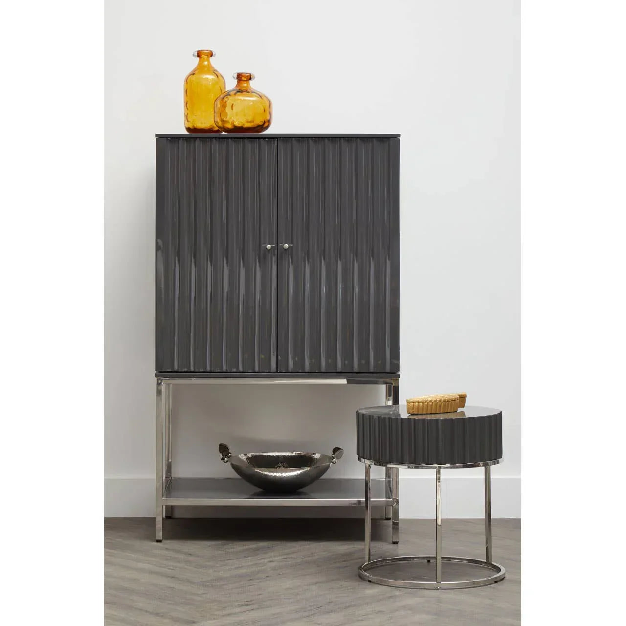 Grey ribbed cabinet with chrome legs, matching round side table, and amber glass vases