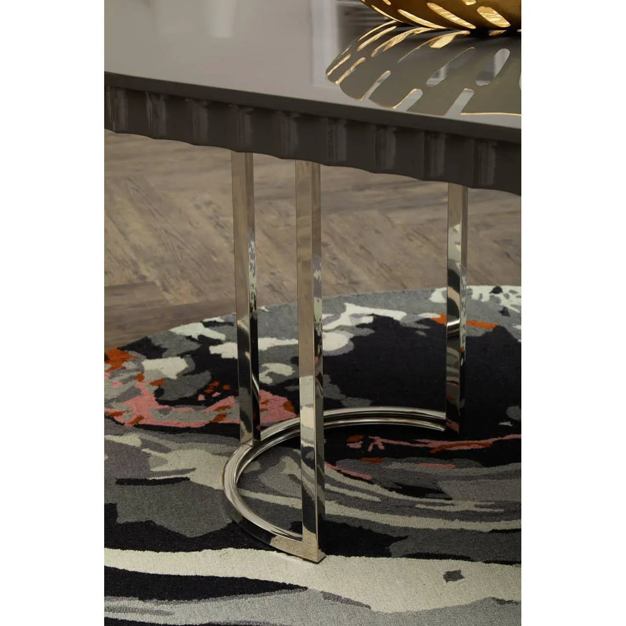 Chrome dining table legs on patterned rug with wood flooring background