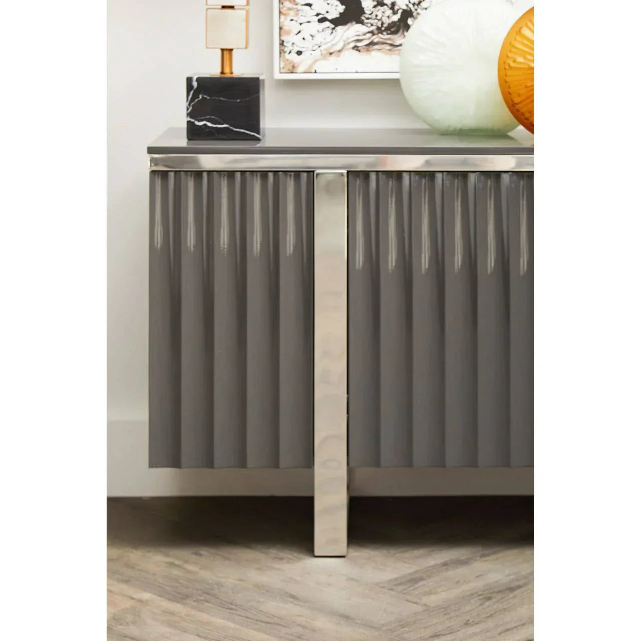 Grey sideboard with fluted doors, chrome handle and decorative vases on top
