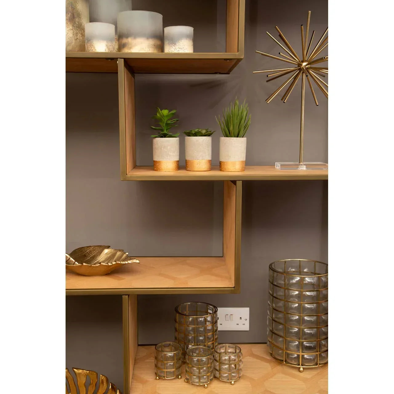Modern shelving unit with decorative vases, gold decor accents, and potted faux plants