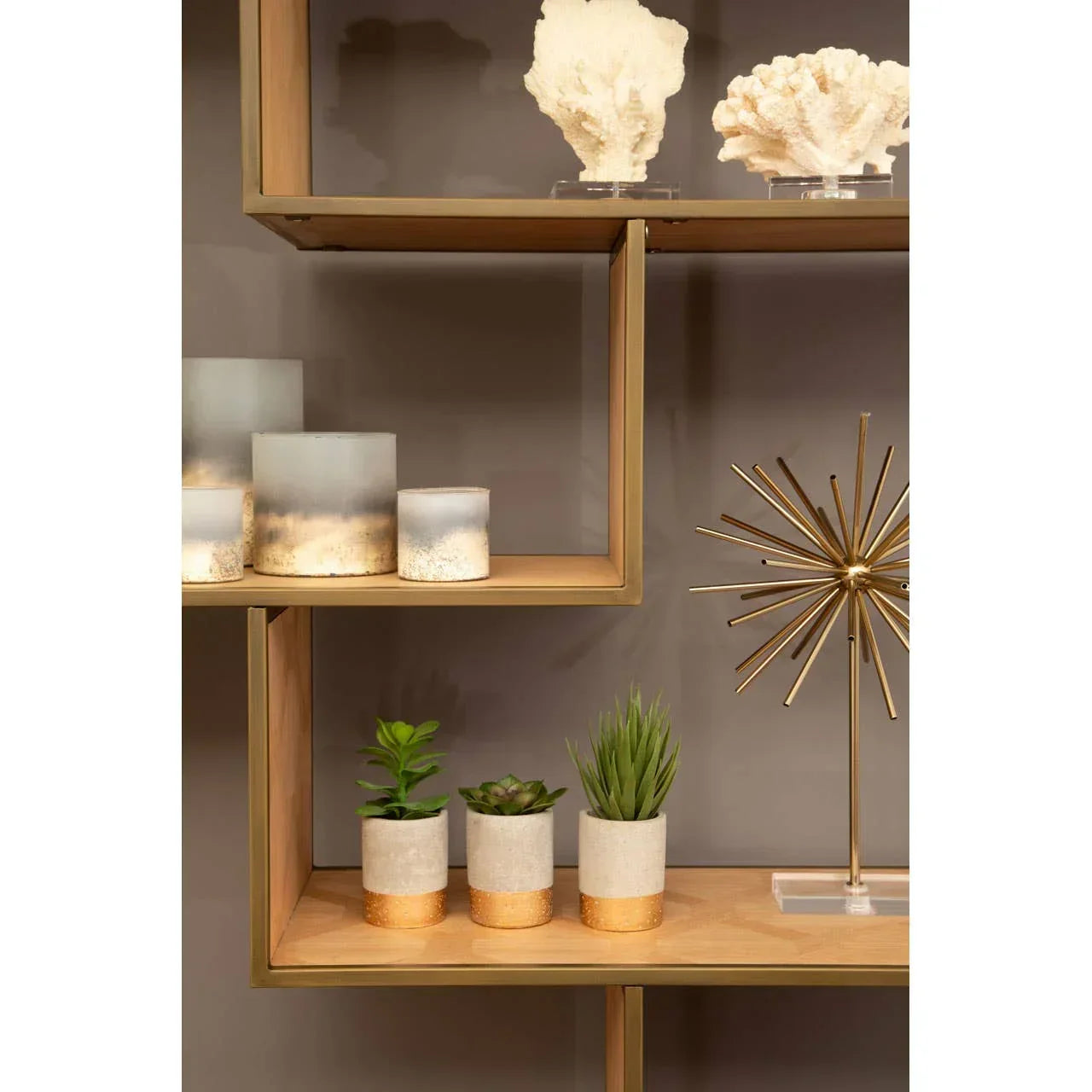 Wooden display shelf with gold decor, candles, artificial plants in gold dipped pots