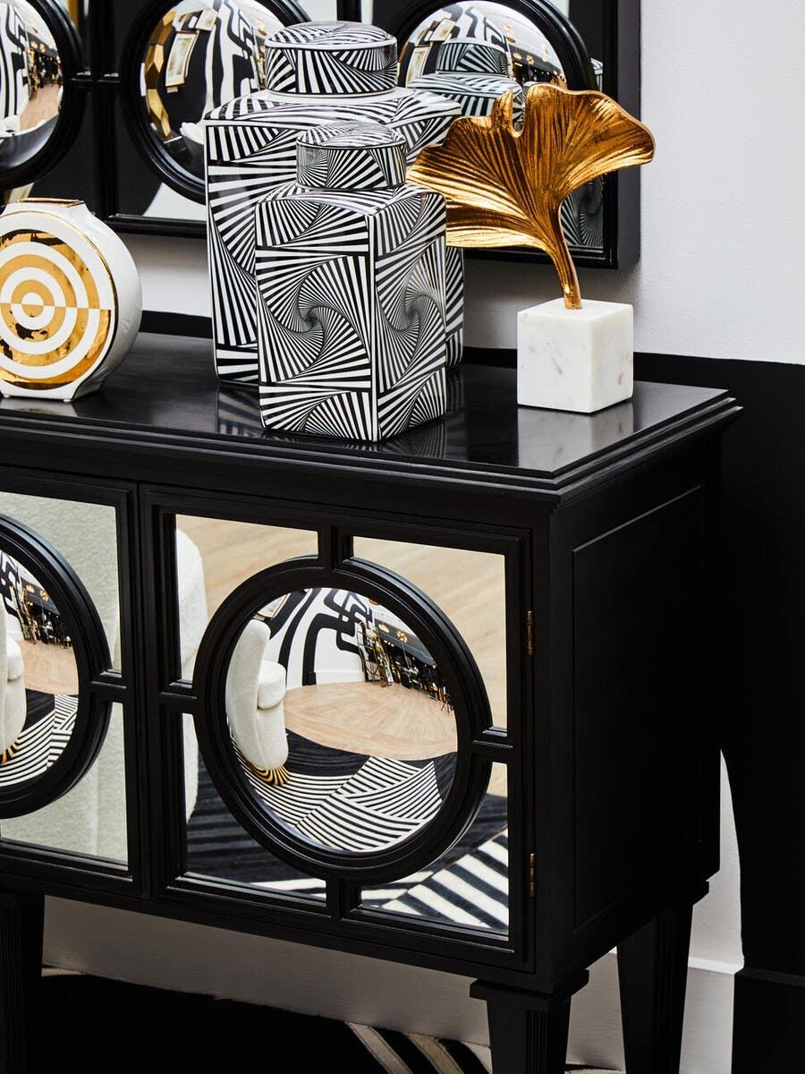 Black mirrored sideboard with geometric vases, gold leaf ornament, monochrome decor accents