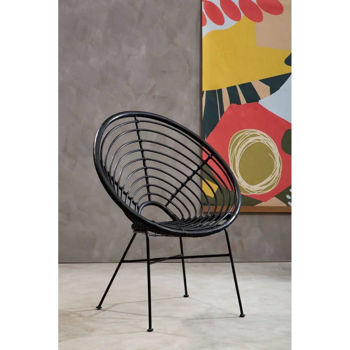 Black rattan accent chair with round seat and metal legs in modern living room