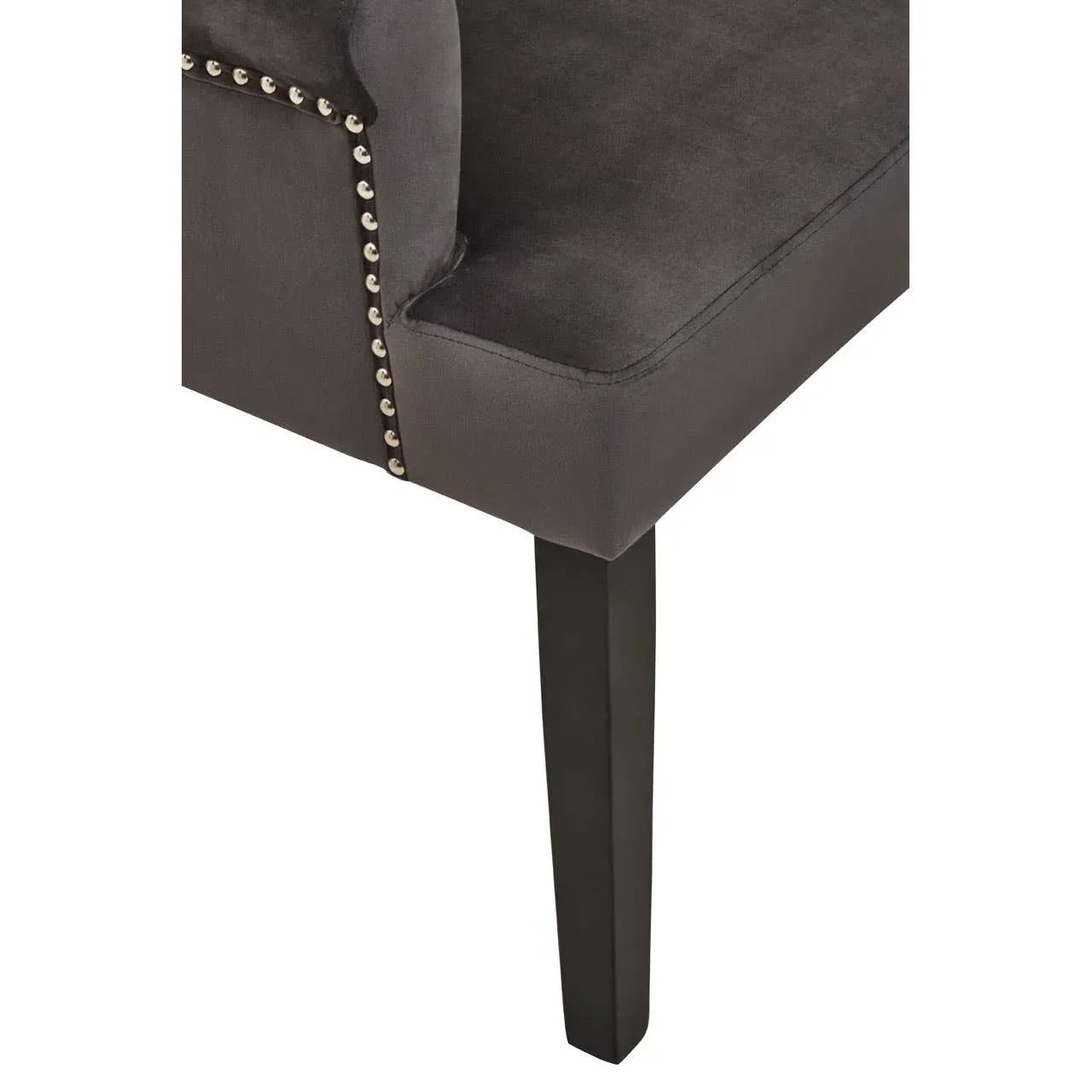 Velvet dining chair corner with studded trim and black wooden leg, close-up view