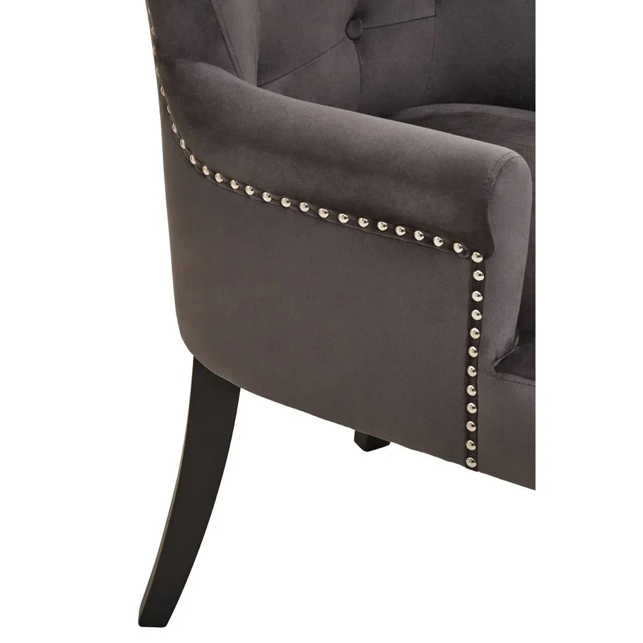 Close-up of grey upholstered armchair with button tufting and silver stud detailing