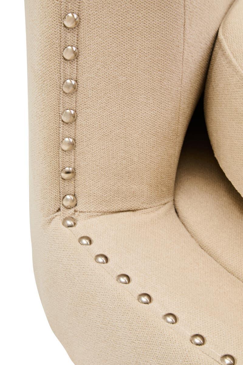 Beige fabric armchair with silver stud trim detail on armrest close-up