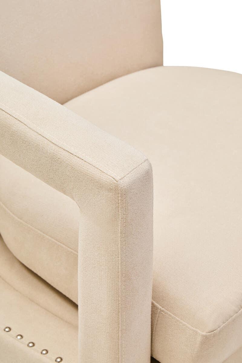 Beige upholstered armchair with soft fabric and stud detail on seat edge, close-up view