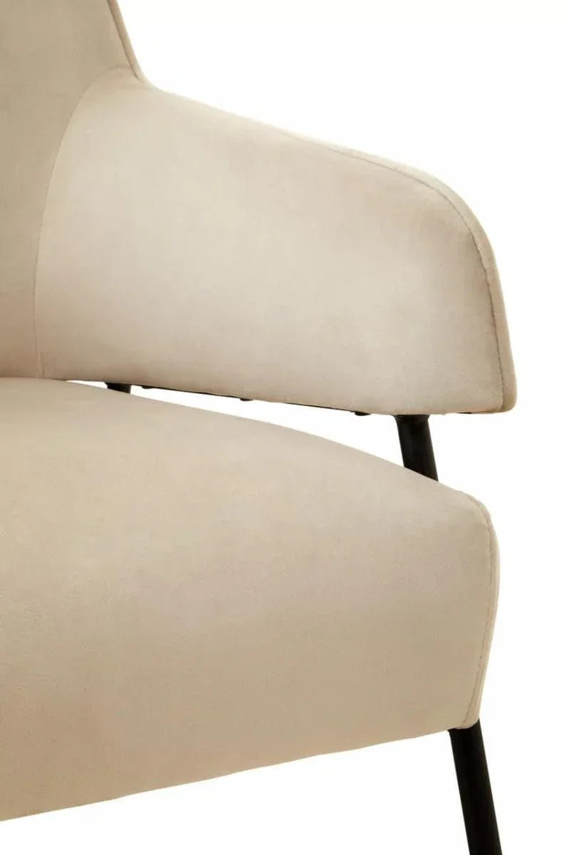 Close-up of beige fabric dining chair armrest and seat with black metal legs