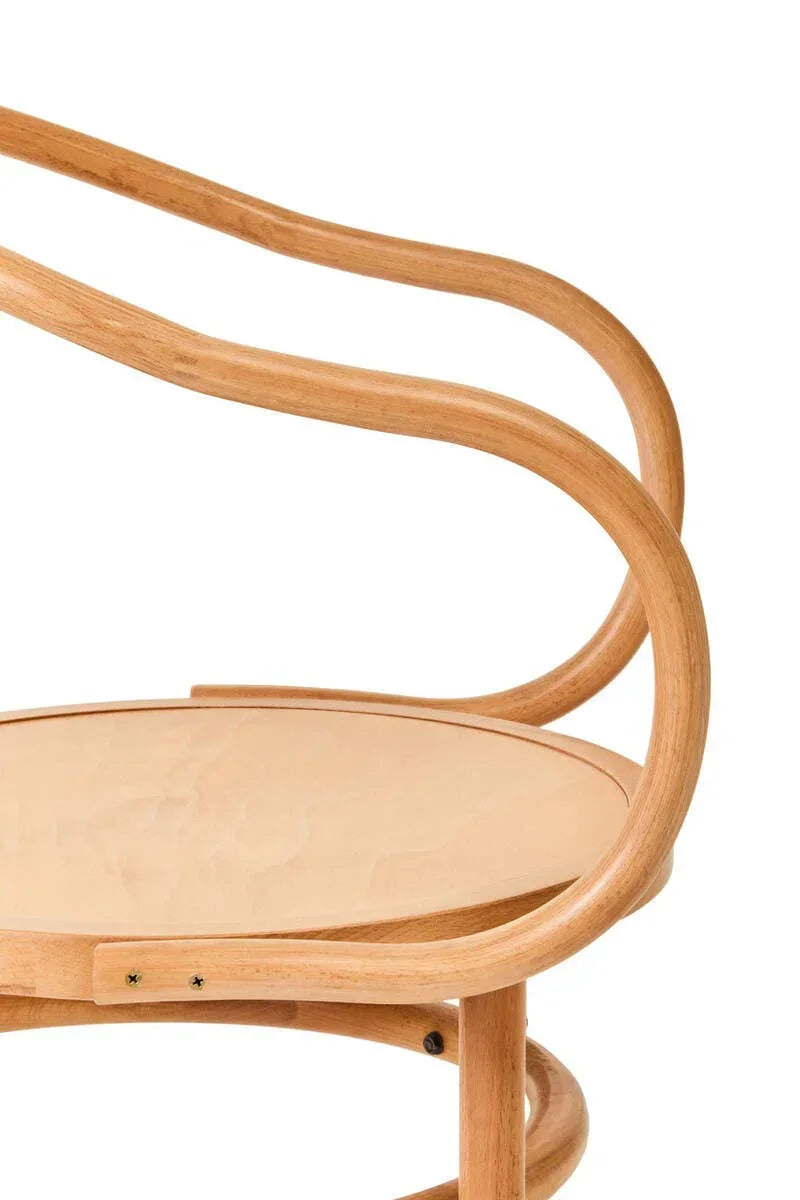 Curved wooden chair arm and round seat in light oak finish, close-up angle