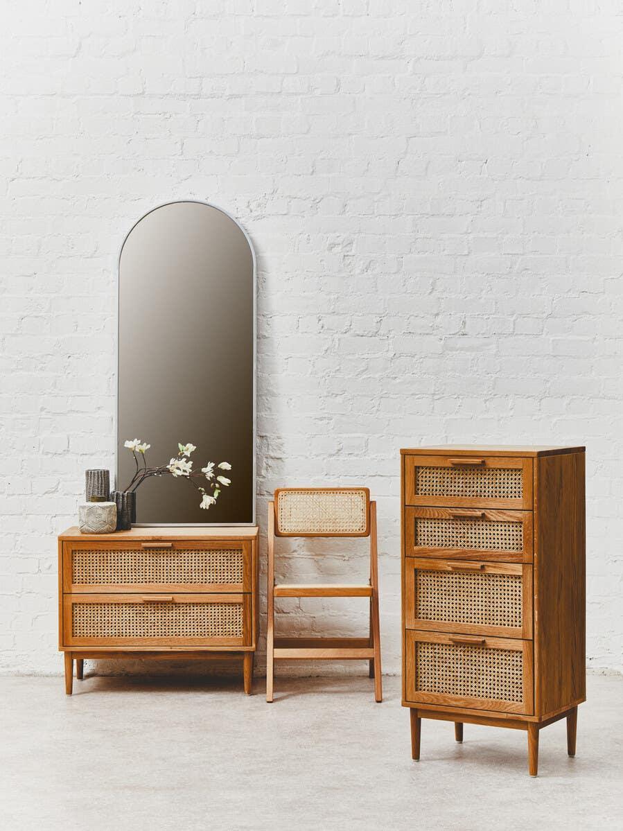 Rattan and wood chest of drawers, dresser, and chair set with an arched mirror on white brick