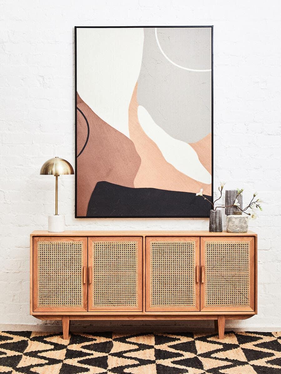 Rattan sideboard with wooden frame, brass lamp, decorative vases and abstract wall art