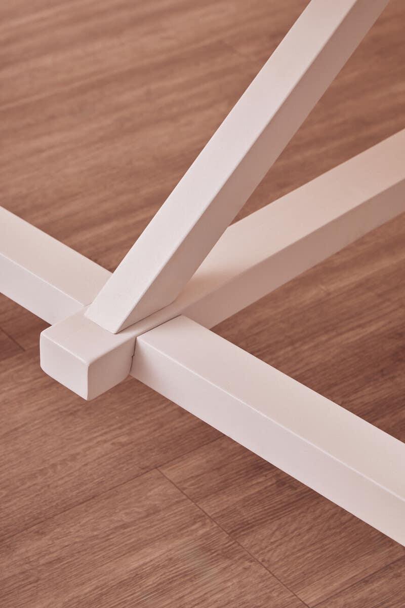 Closeup of white metal table legs with cross base on wood floor