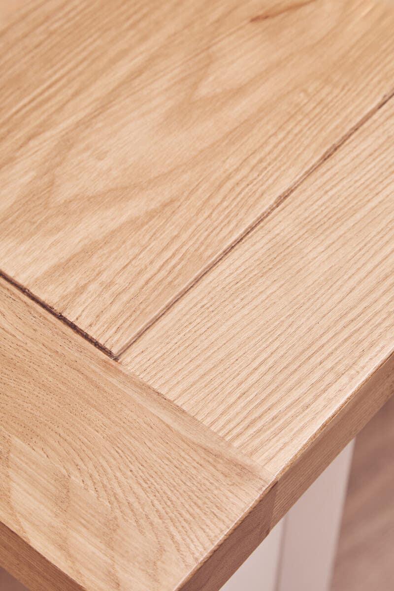 Closeup of light oak dining table corner showing wood grain and smooth finish