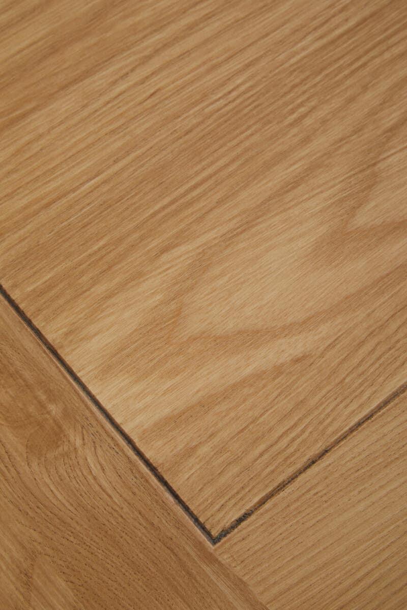 Close up of light oak wood table top with visible grain and joined edge