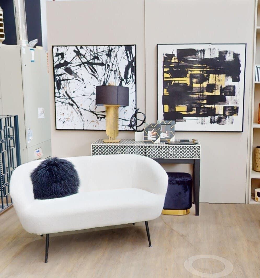 Modern white sofa with black faux fur cushion and console table in contemporary showroom