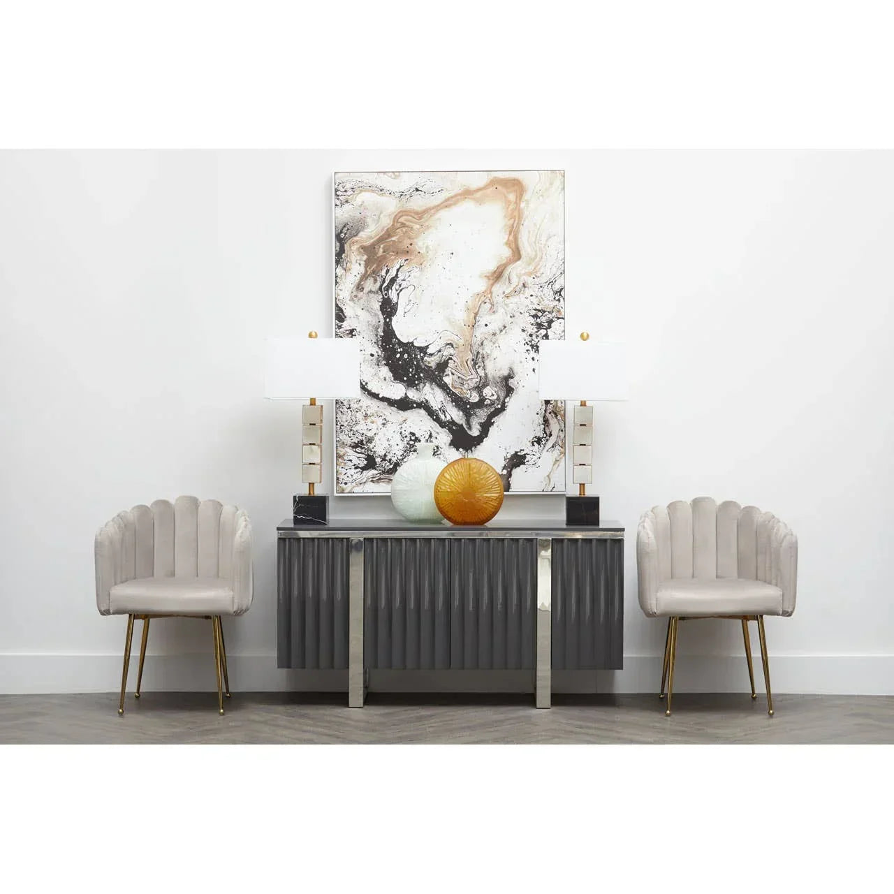 Modern sideboard with marble lamps, abstract art, and two beige velvet accent chairs