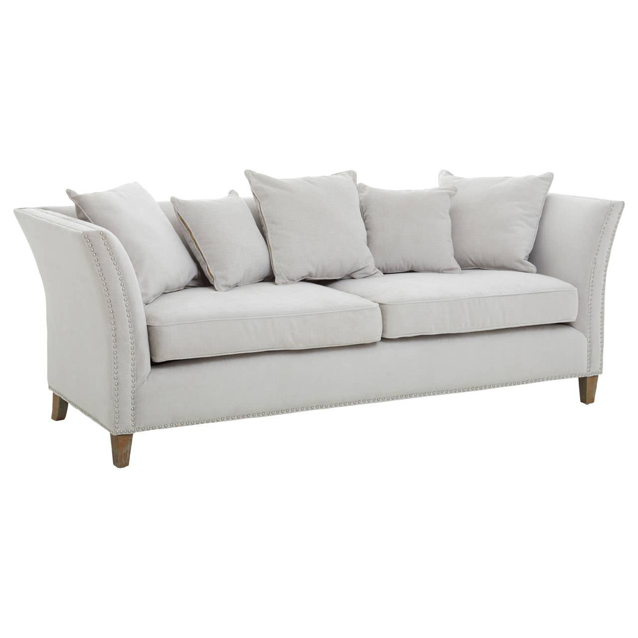 Three-seat sofa upholstered in light grey fabric, featuring a curved backrest and armrests. The sofa is adorned with several plush cushions for added comfort and is supported by wooden legs