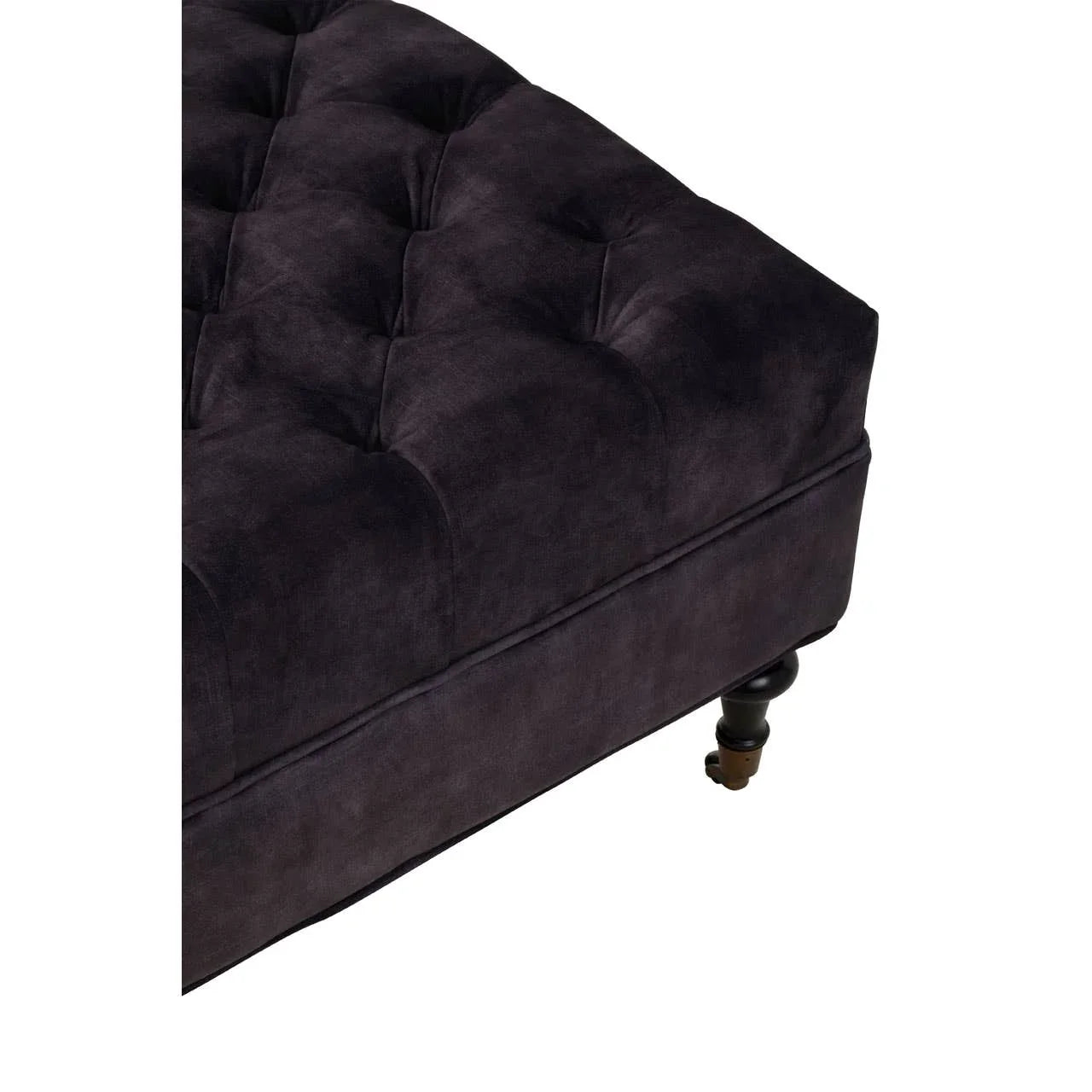 Plush dark velvet ottoman with button tufted upholstery and black turned wooden leg