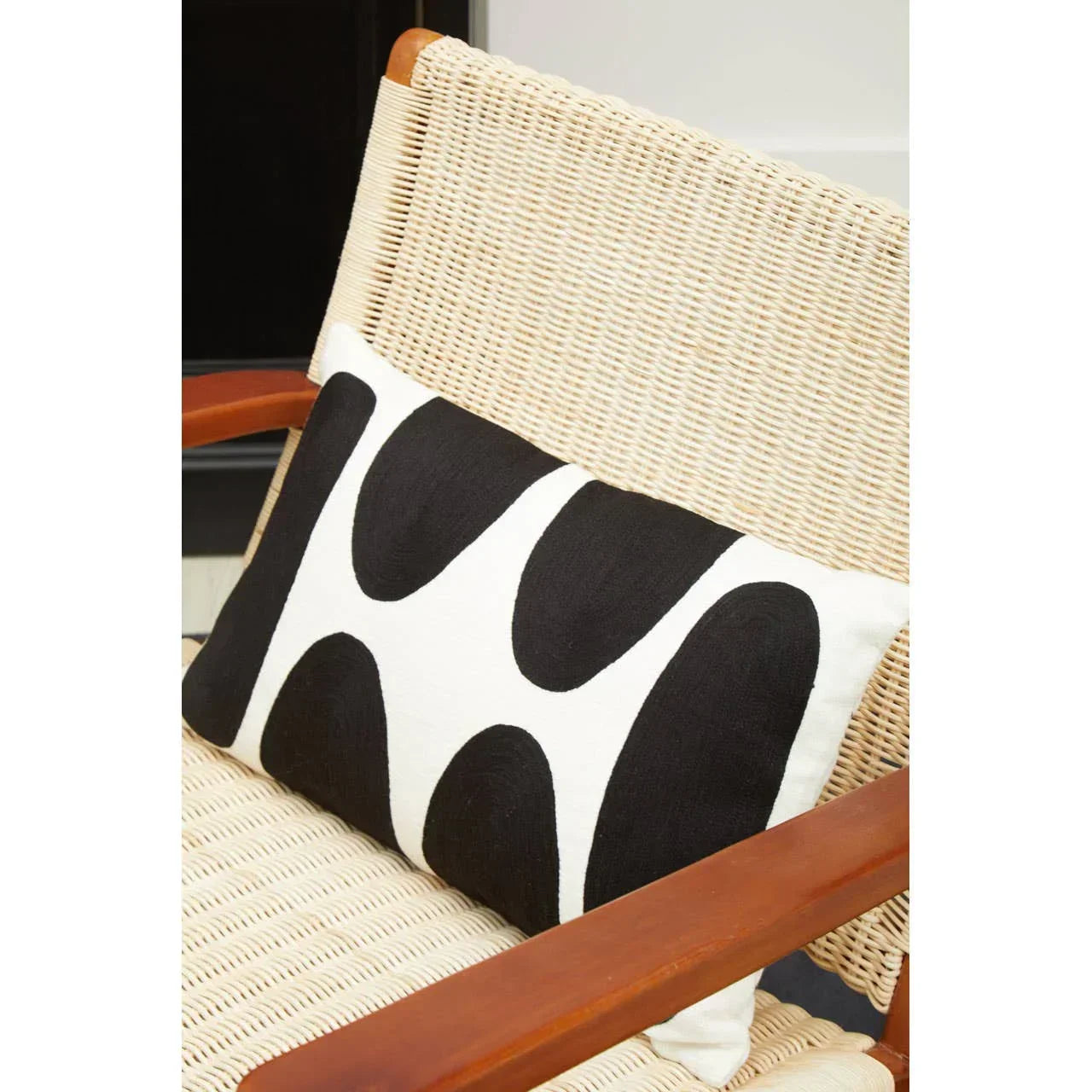 Woven lounge chair with black and white geometric cushion on seat