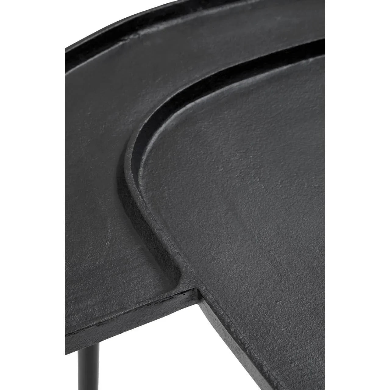 Close detail of black metal side table top with curved edge and textured finish