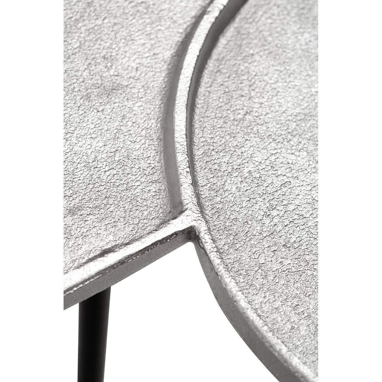 Close-up of textured silver metal table top with geometric design and black leg