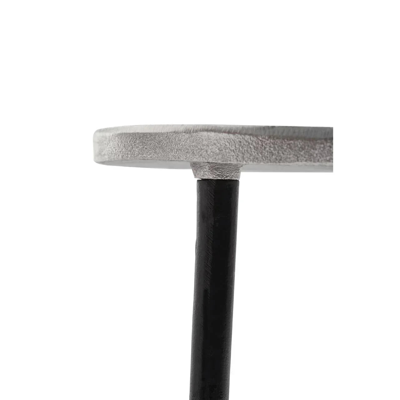 Close detail of metal side table top with black leg and textured silver finish