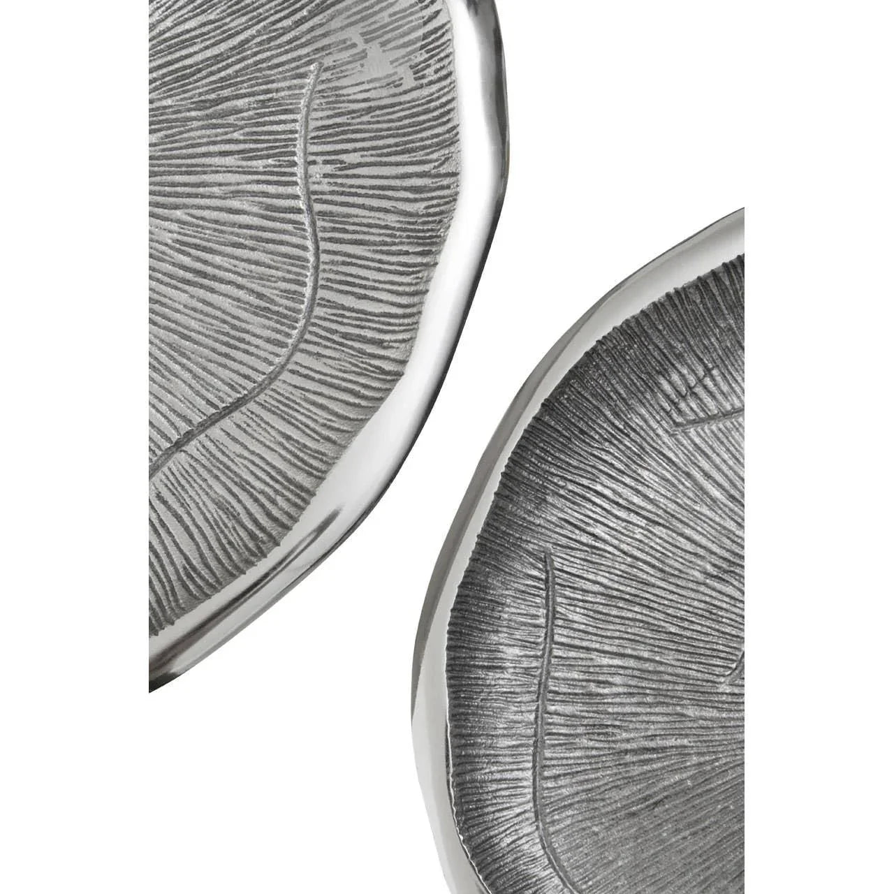 Close up of two textured silver decorative trays with leaf pattern detail