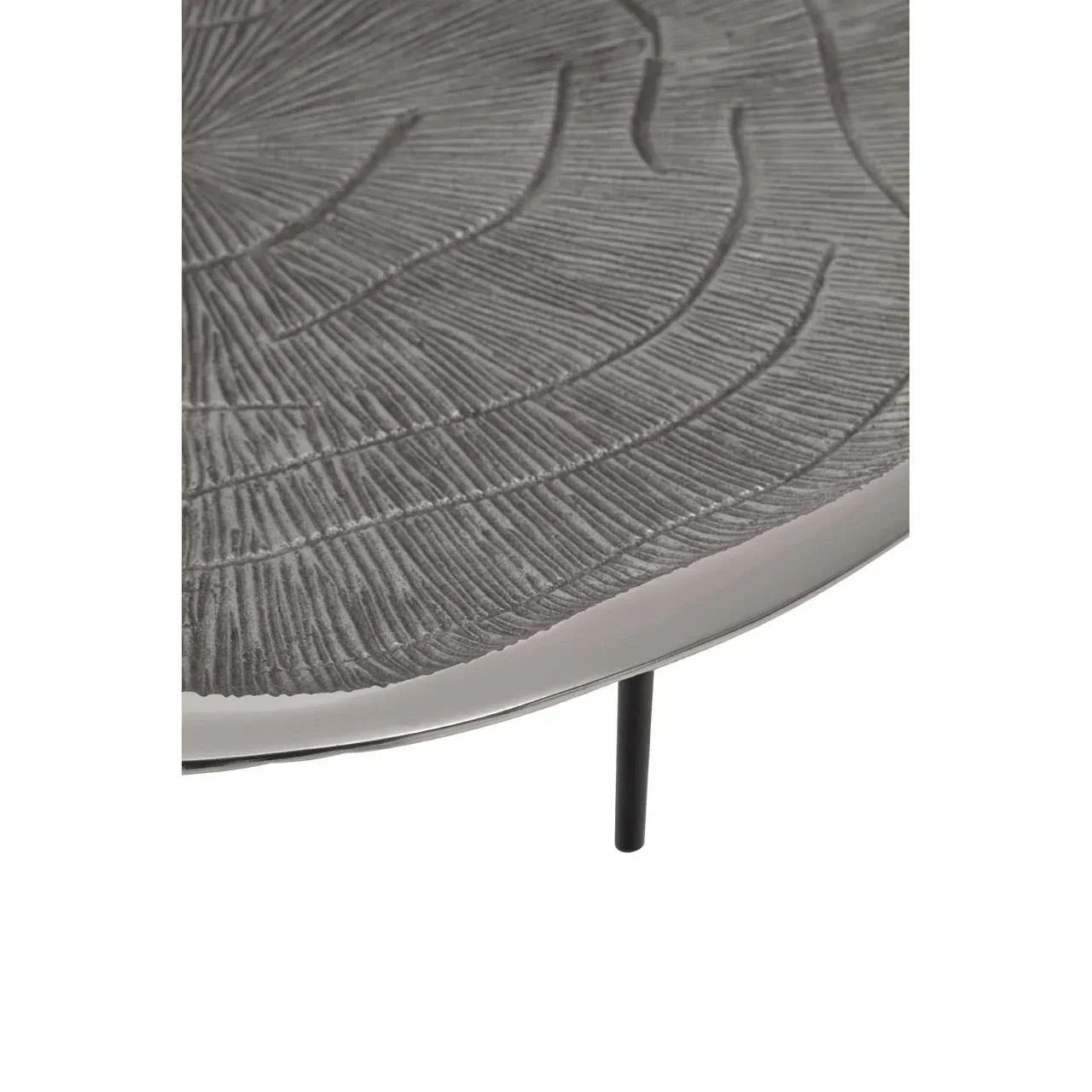 Textured metal coffee table top with leaf pattern and slim black leg close-up