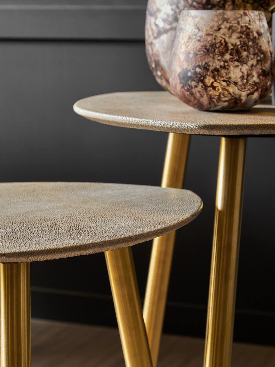 Round side table with textured surface and gold metal legs, marble vase on top
