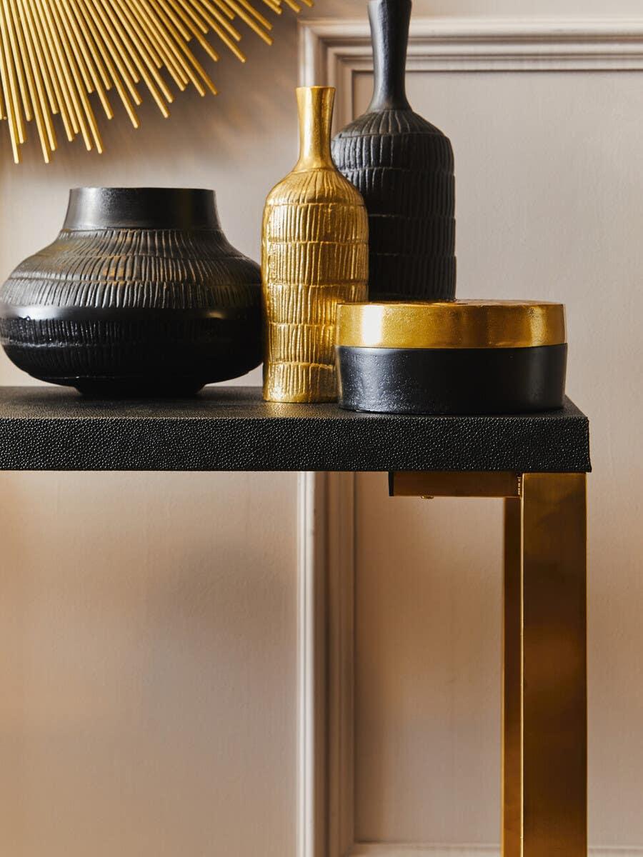 Black and gold decorative vases on modern console table with gold metal legs