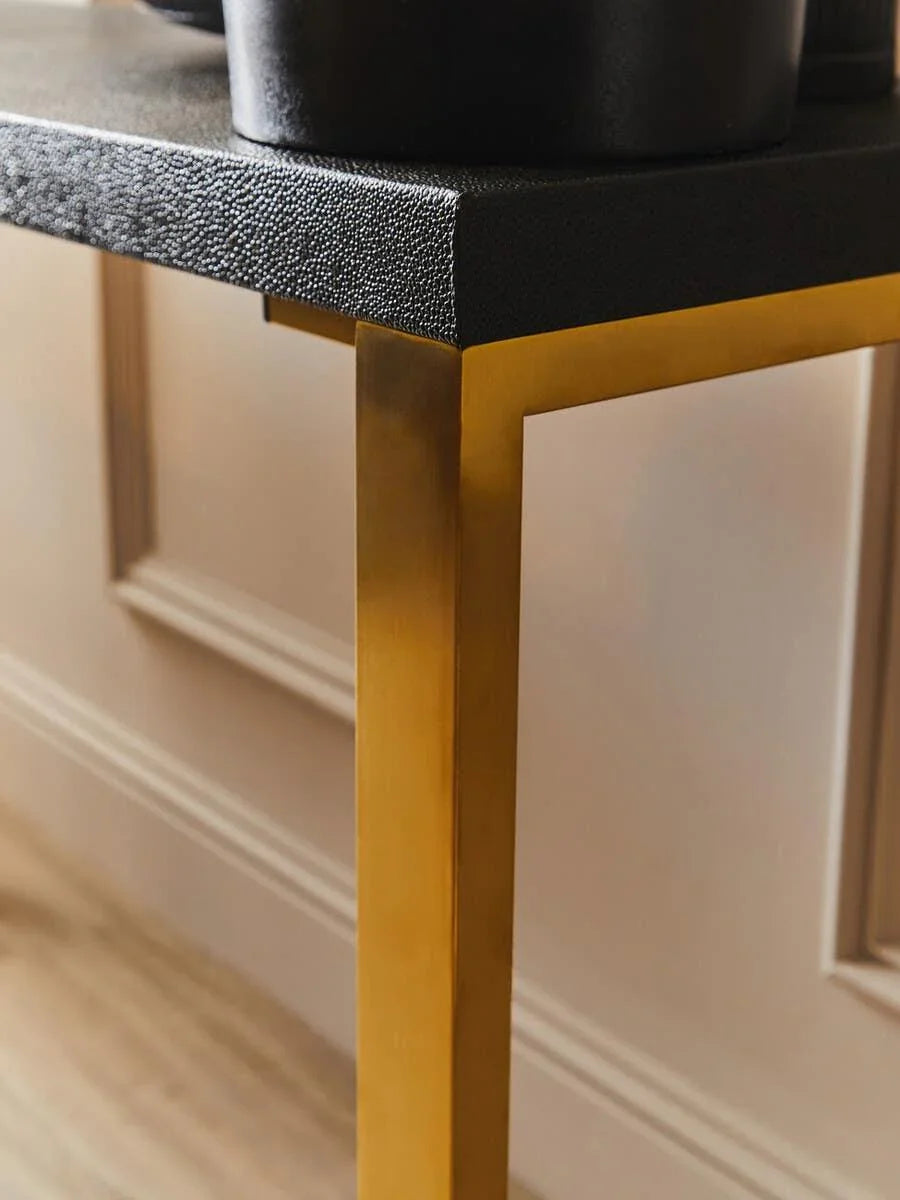 Textured black console table with gold metal legs in modern interior setting