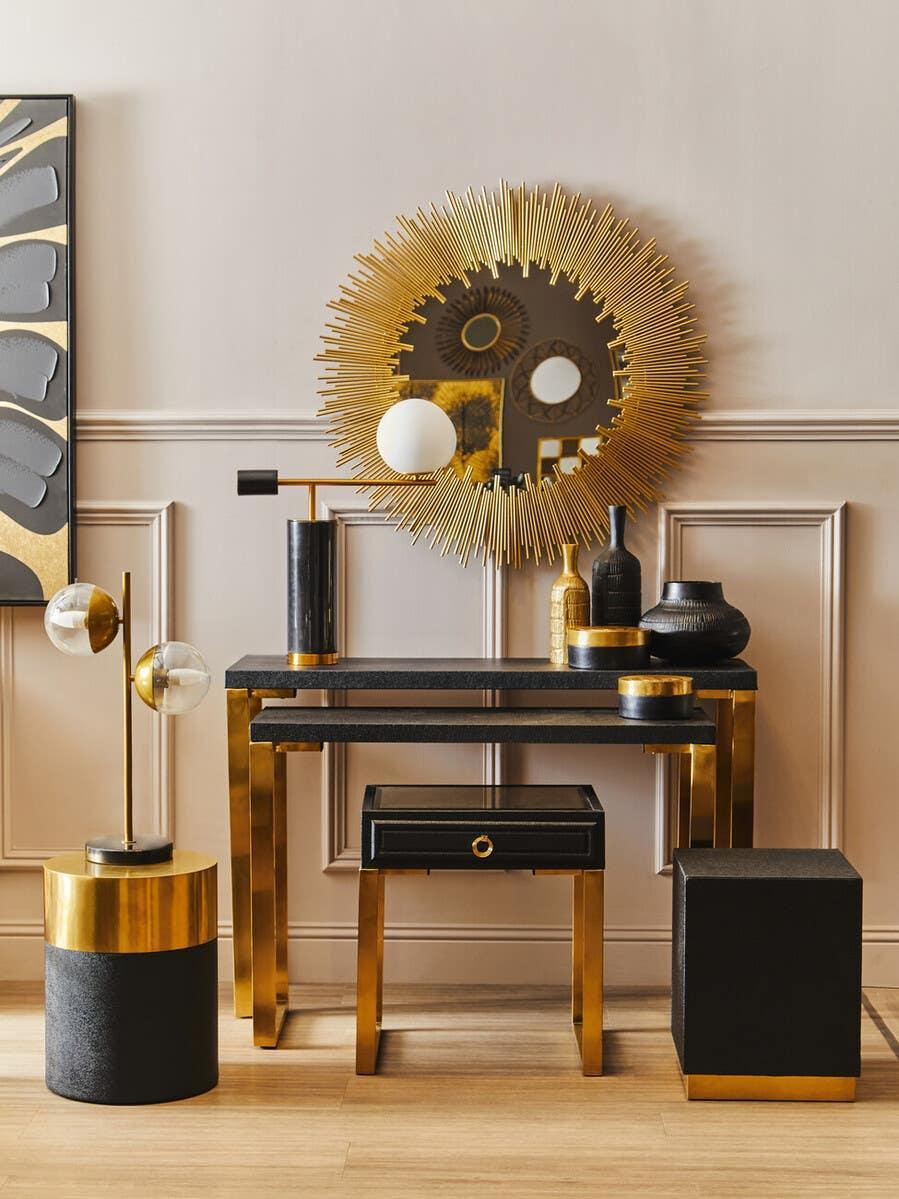 Black and gold console table set with sunburst mirror, modern lamps and accent vases