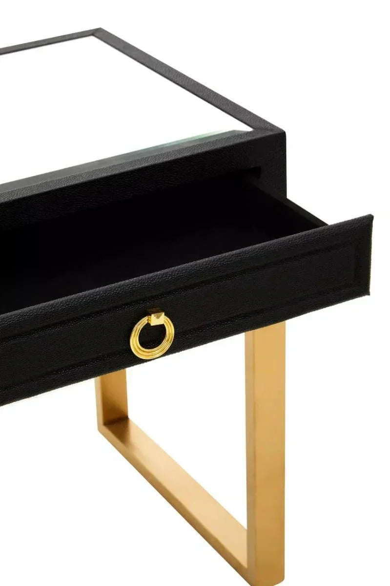 Black console table with gold metal legs and open drawer featuring gold ring handle