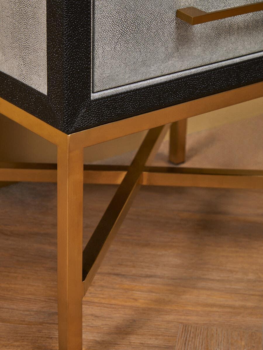 Modern furniture leg with gold metal frame and textured drawer panel on wood flooring