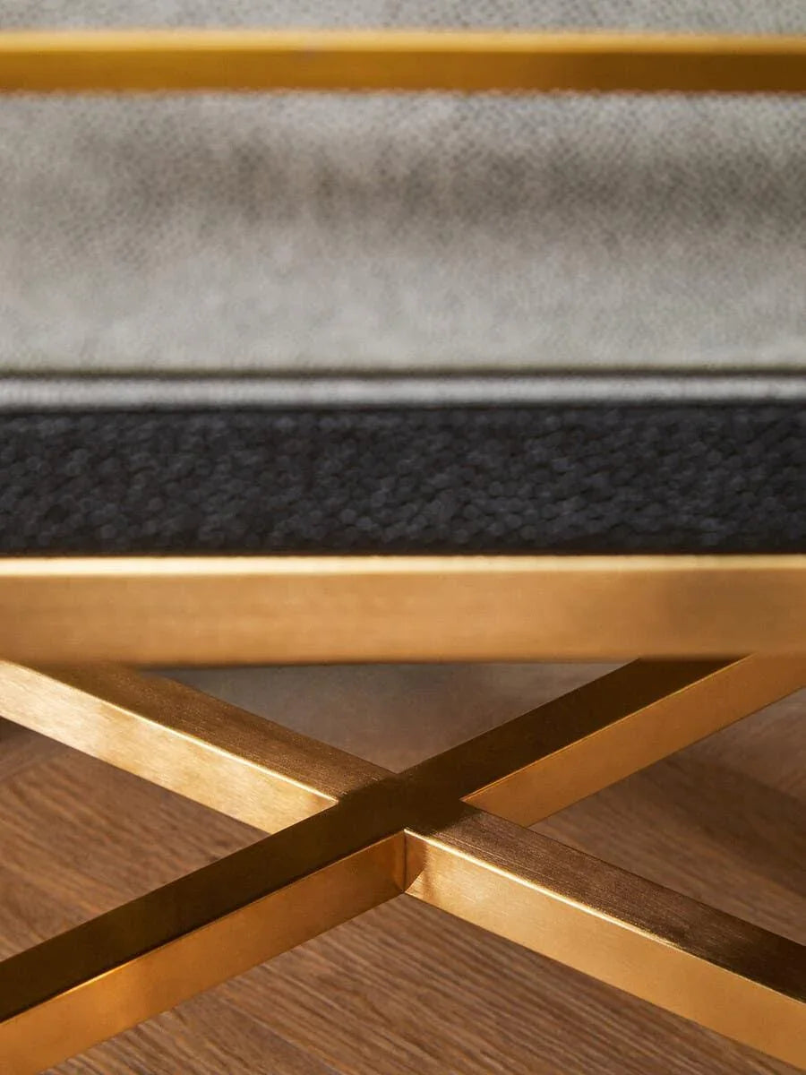 Gold metal coffee table base with cross leg design on wood flooring