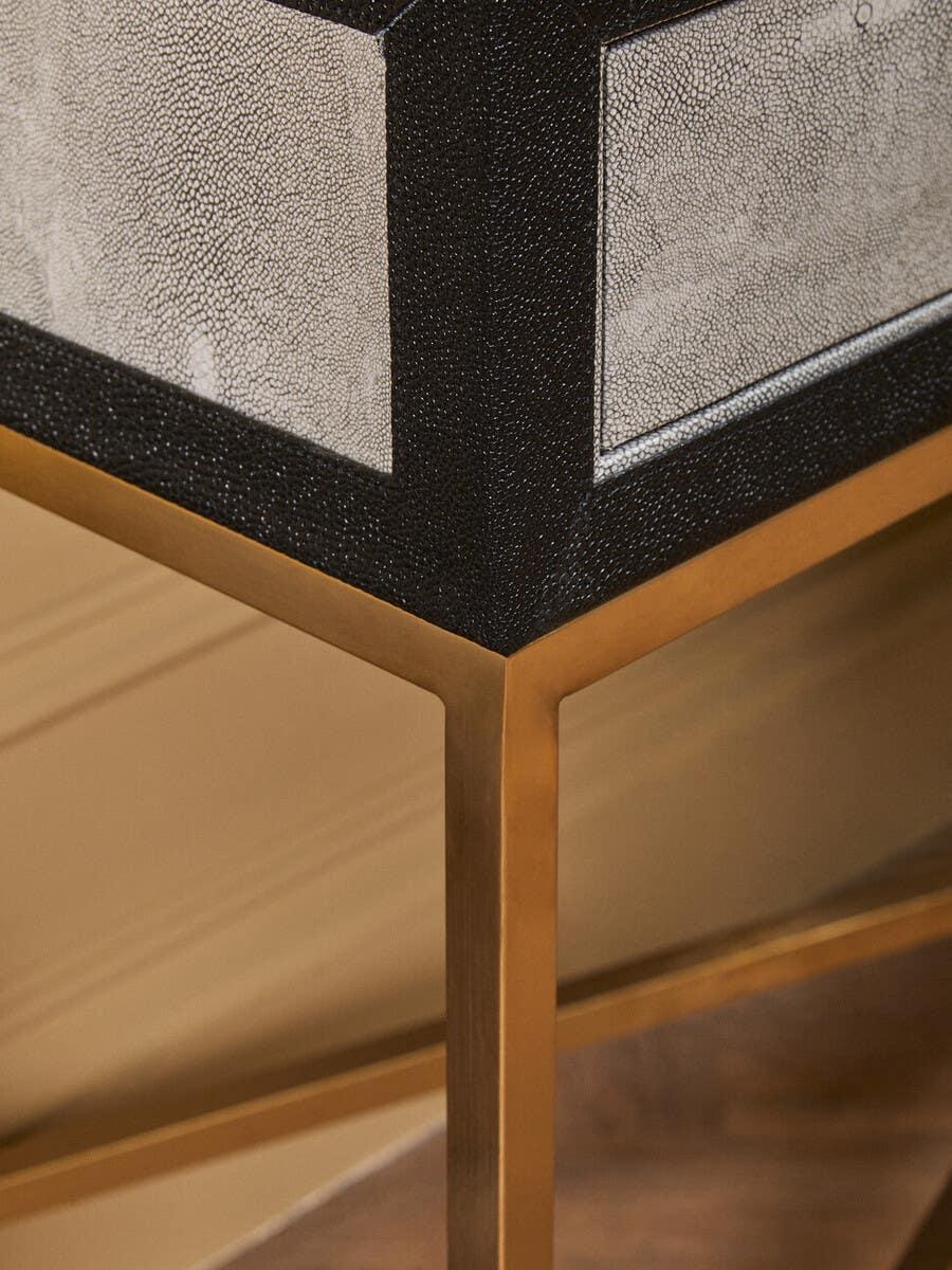 Close up of textured side table with gold metal legs and black trim accent