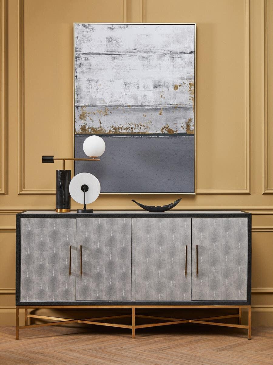 Modern grey sideboard with gold legs and handles against beige wall paneling