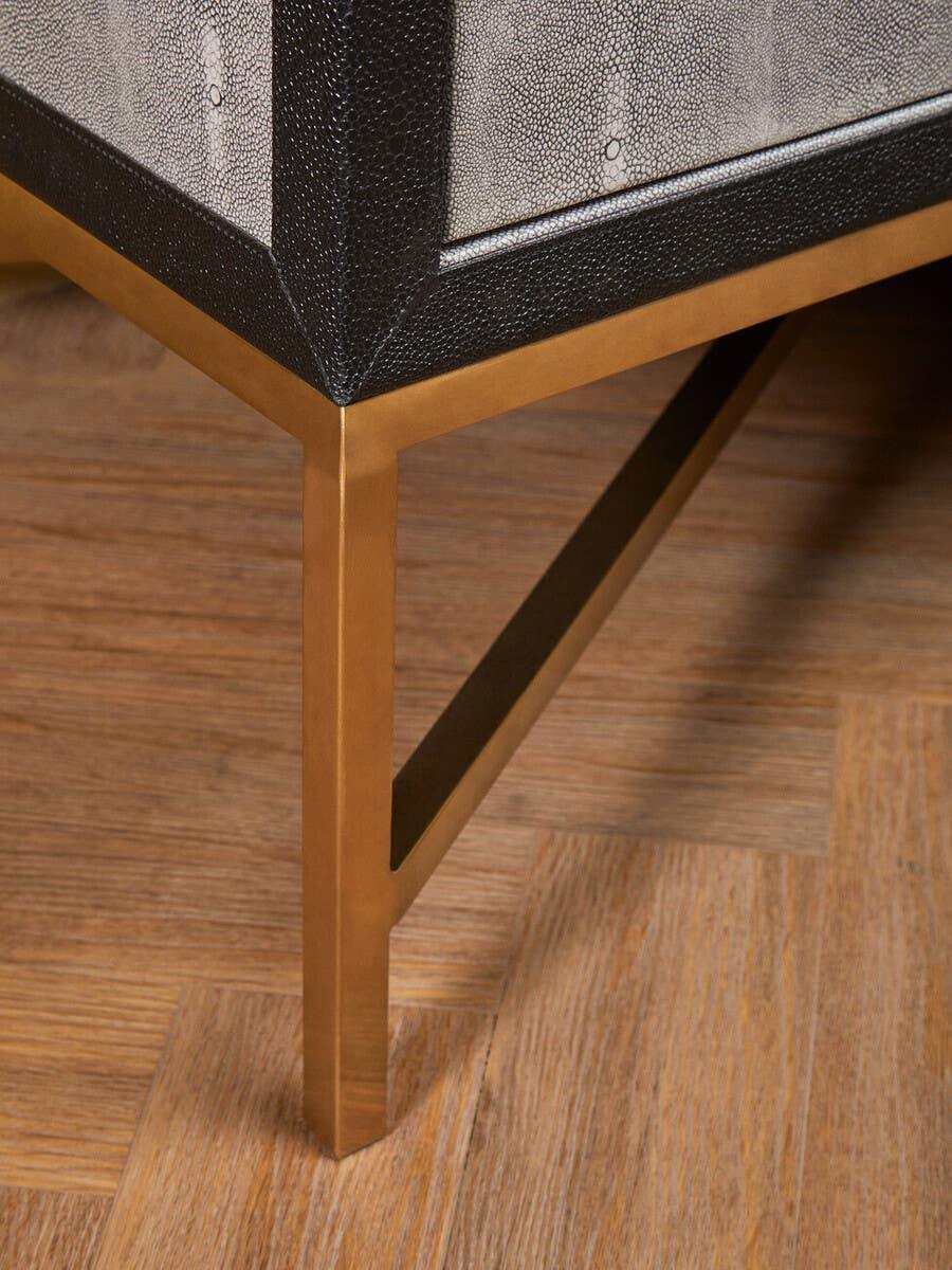 Close up of furniture corner with textured black and grey upholstery and gold metal leg