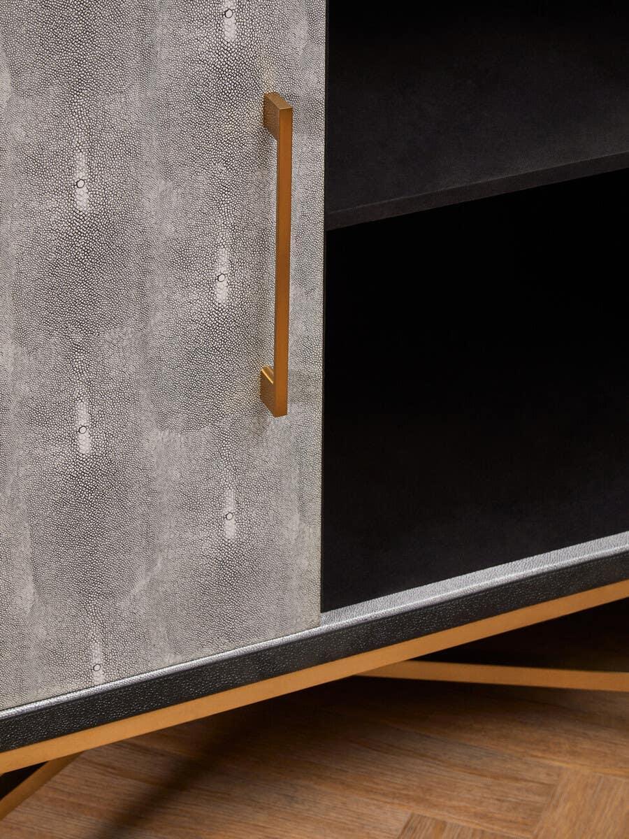 Grey textured cabinet door with gold handle and open shelving on wood floor