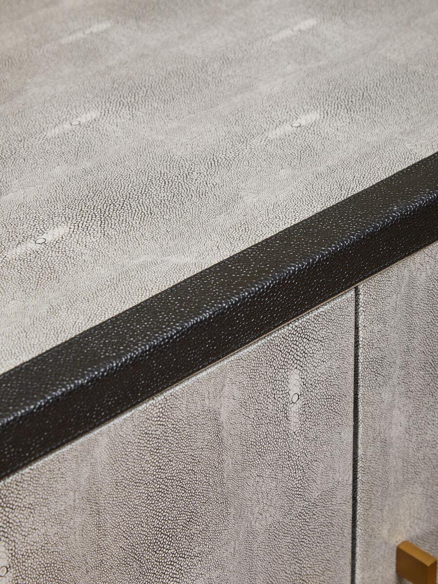 Closeup of textured grey sideboard cabinet with black trim and gold handle detail