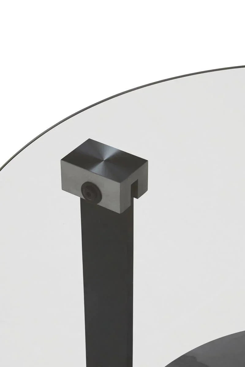 Close-up of round glass coffee table with black metal leg and corner fixture