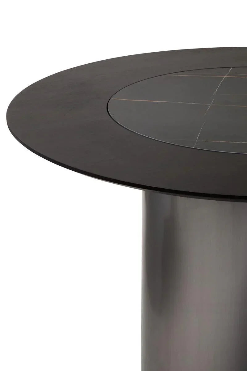 Round black dining table with central stone inlay and cylindrical metal base, side view