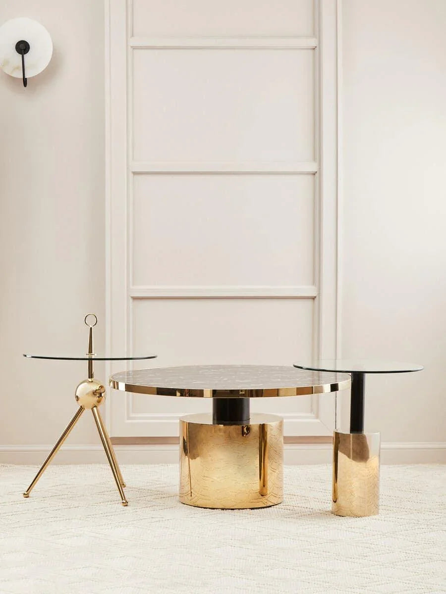Gold and glass coffee table set with round tops on cream textured rug against beige wall panel