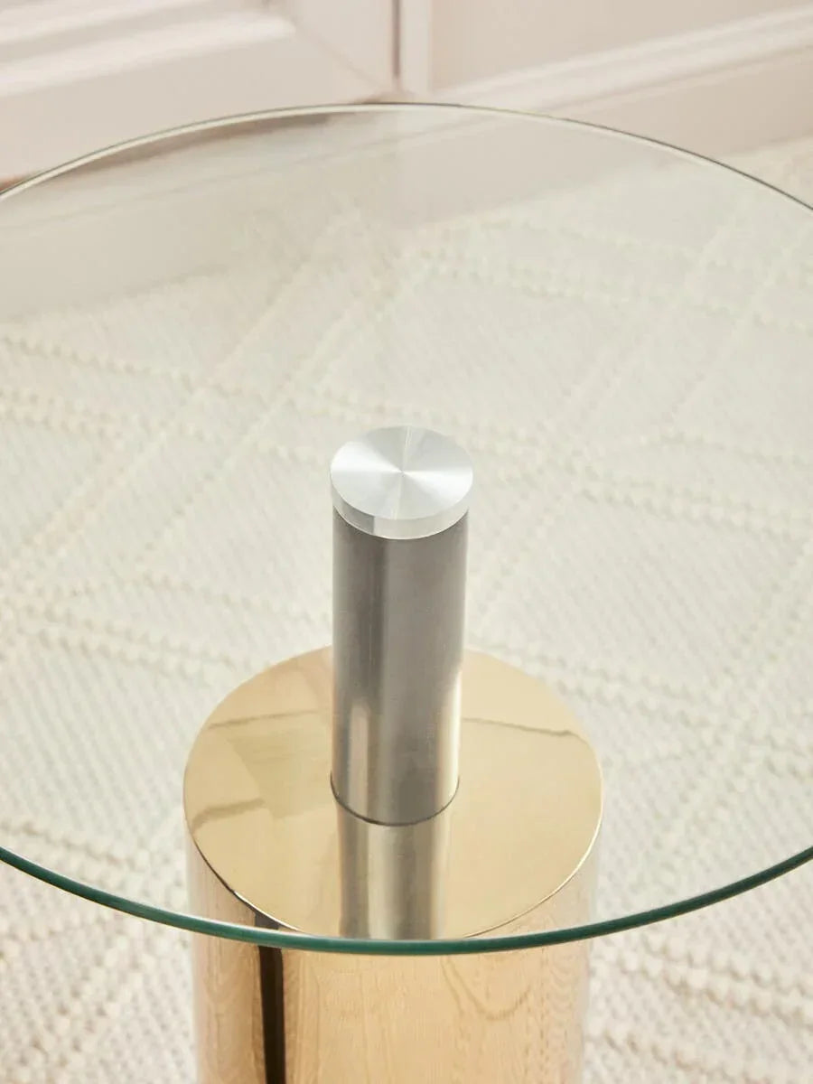 Round glass top side table with gold base and metal centre support on textured rug