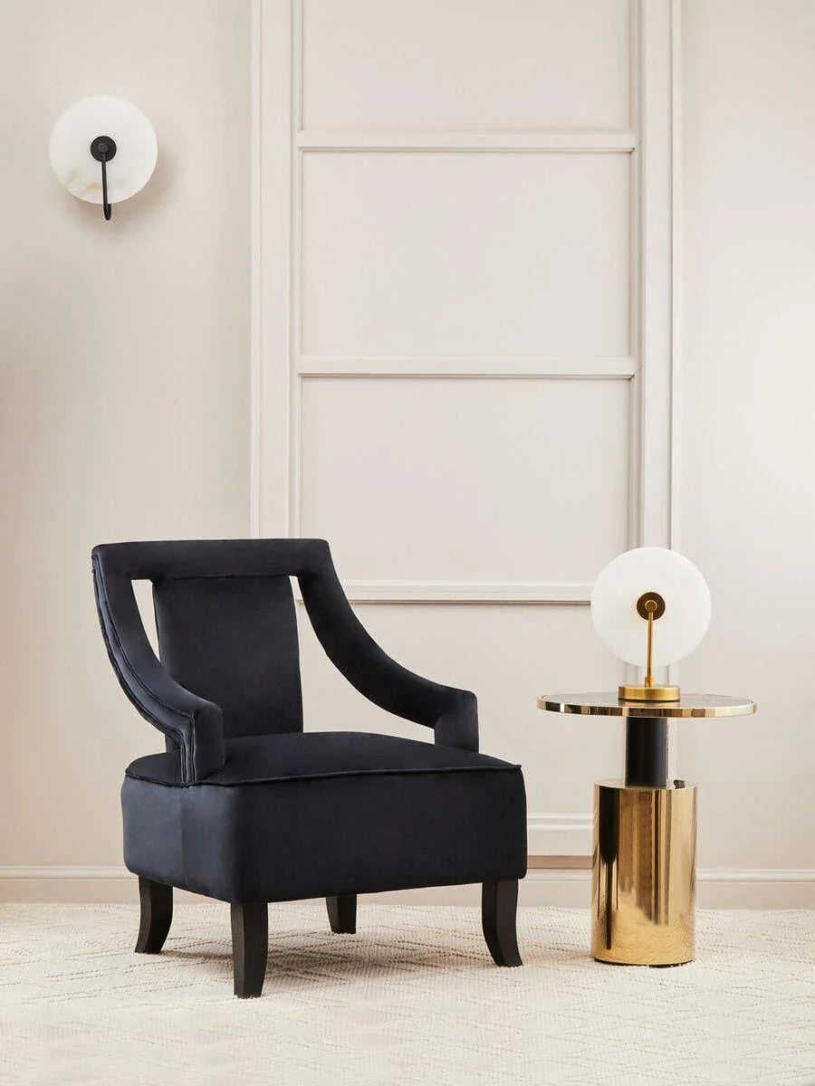 Black velvet accent chair next to gold side table with white lamp in modern living room