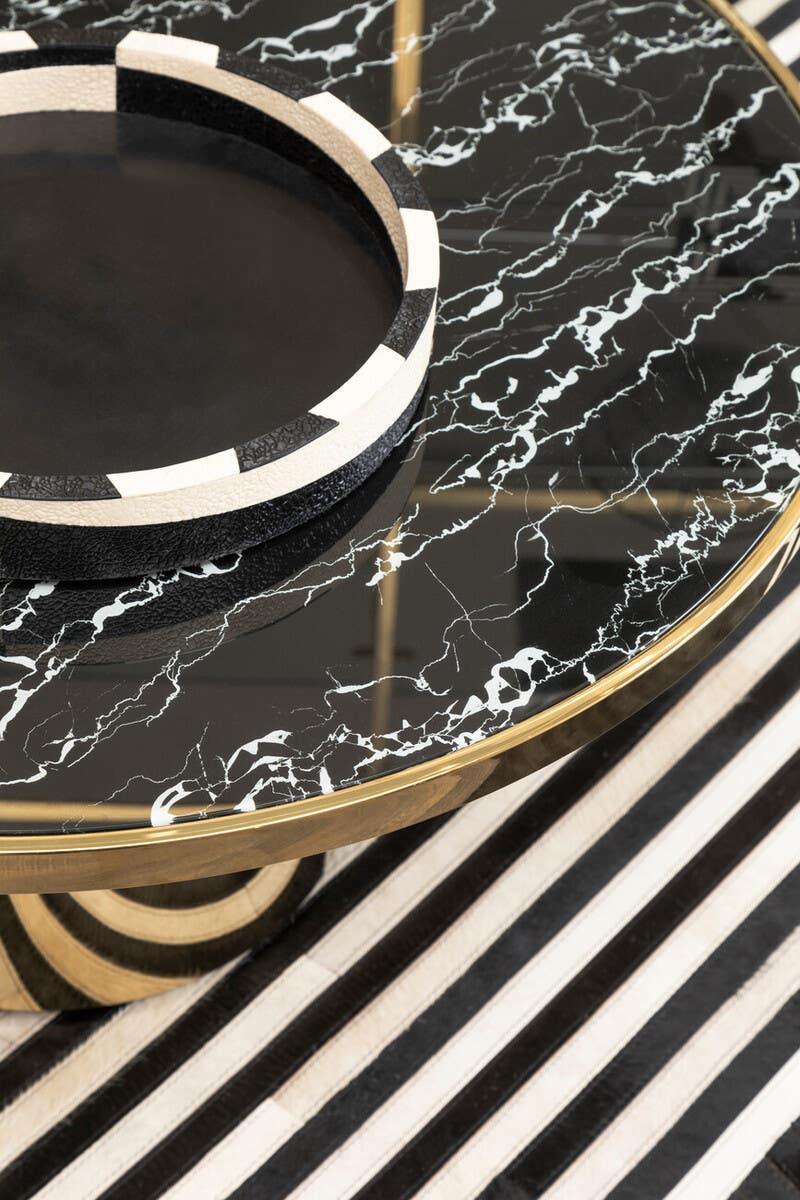 Round black marble coffee table with gold edge and monochrome striped tray on top