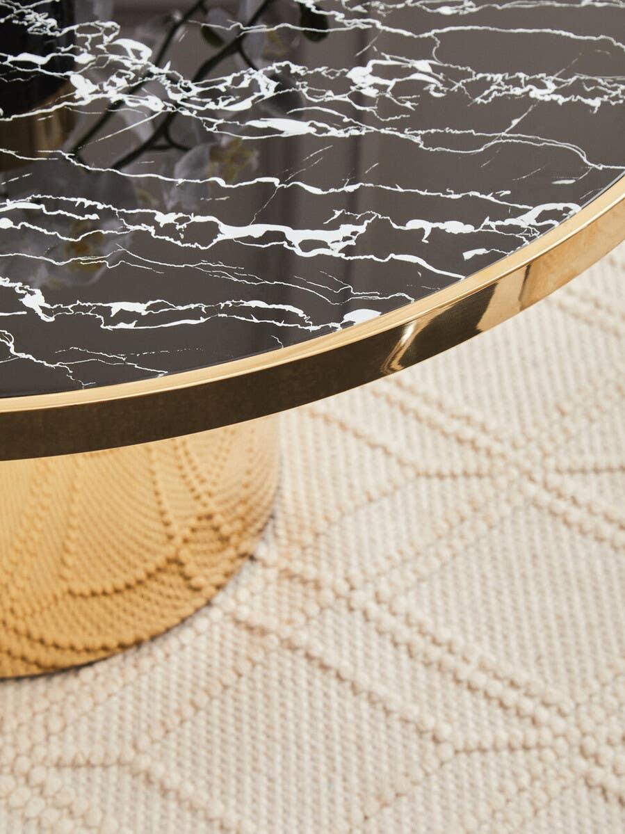 Round black marble coffee table with gold base on textured cream rug