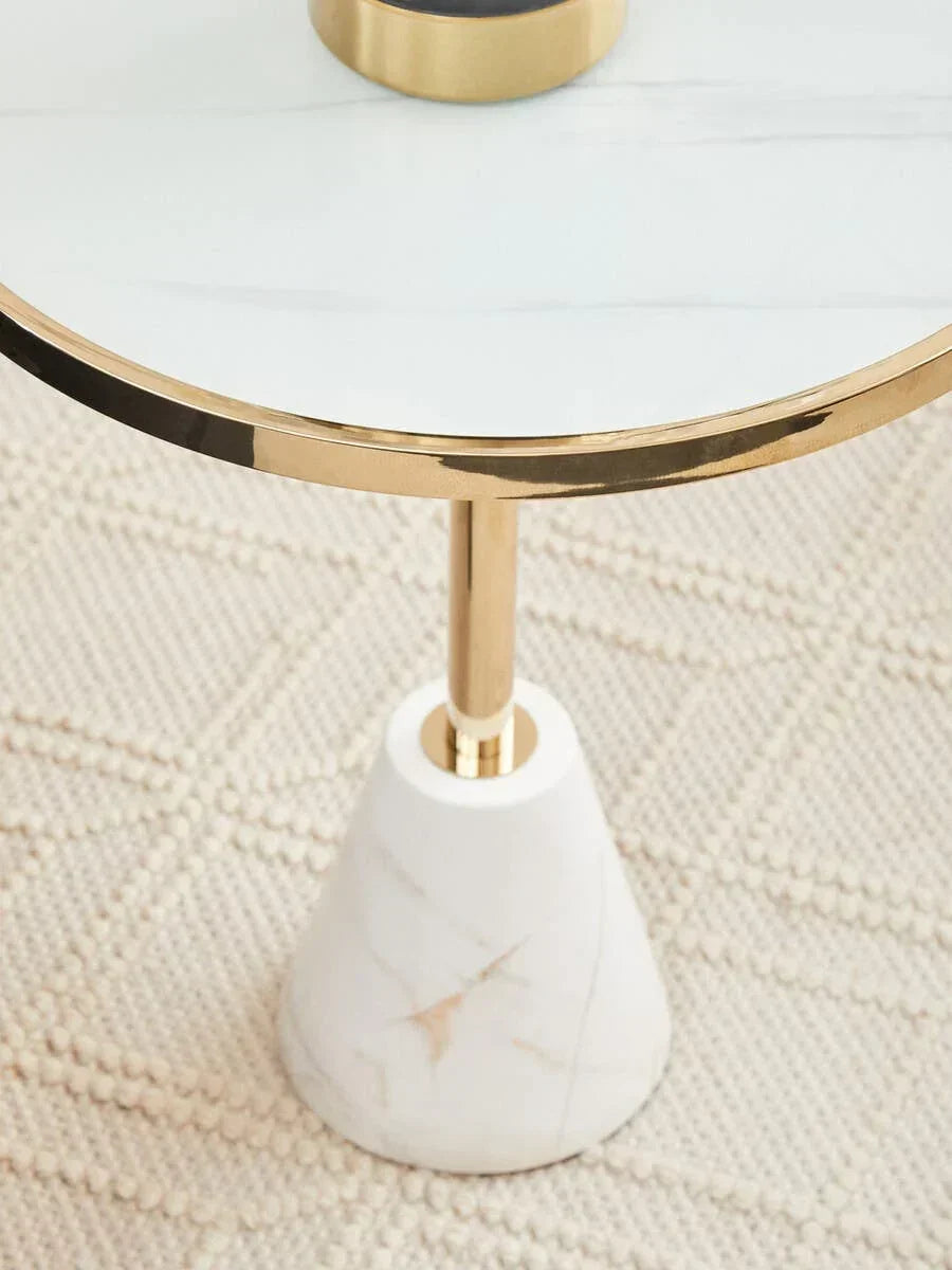 Round marble side table with gold frame and base on textured cream rug