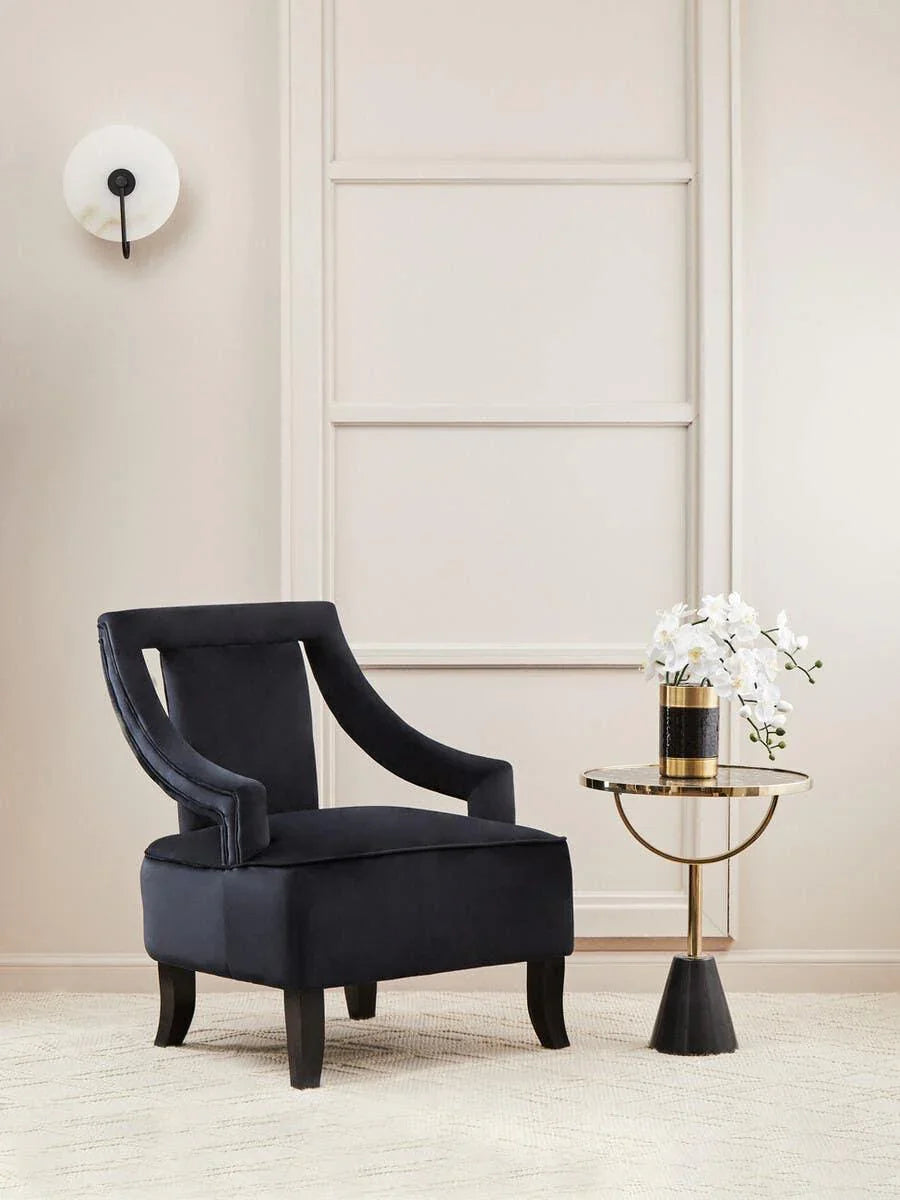 Black velvet accent chair beside gold and black side table with white flowers