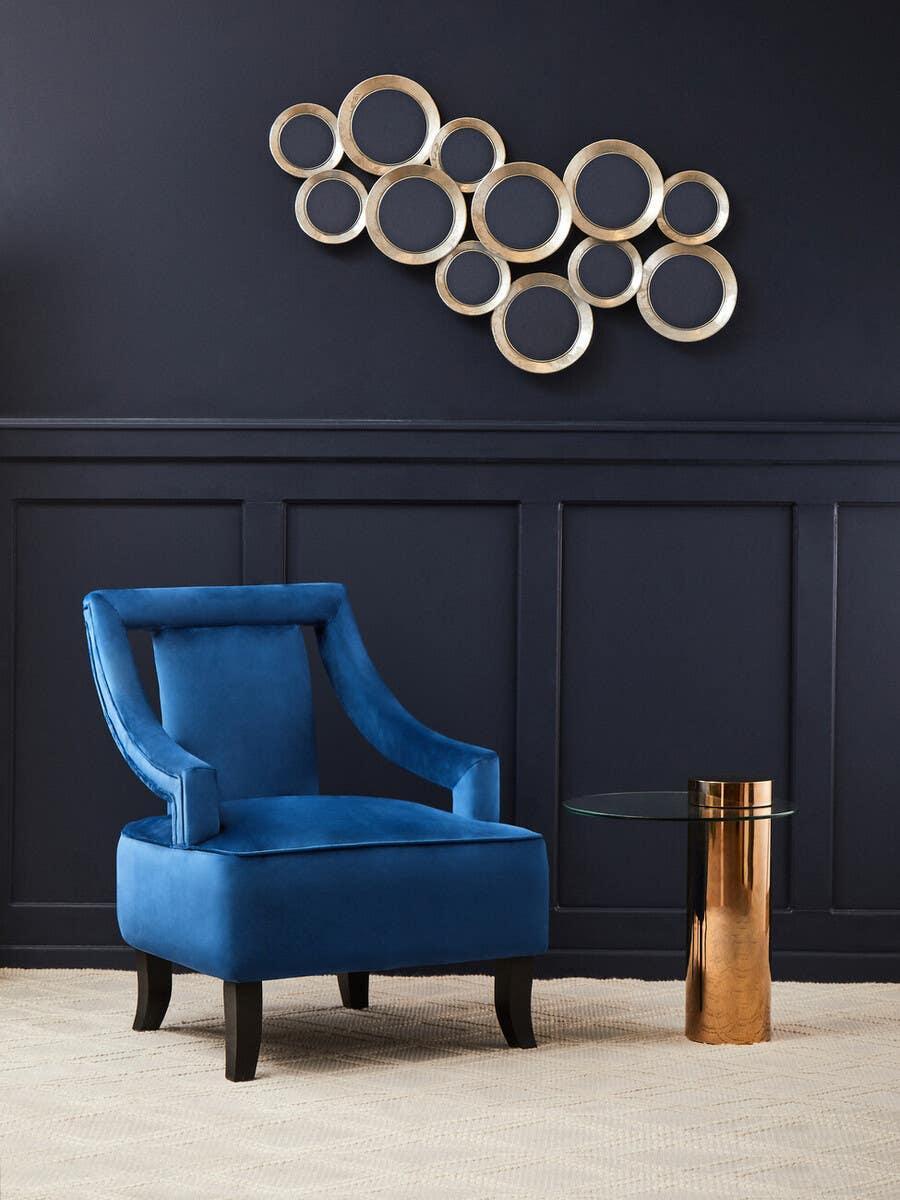 Blue velvet accent chair with black legs beside glass and gold metal side table in modern room